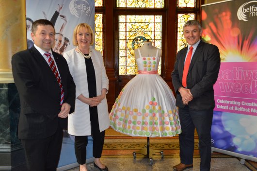 Marie Therese McGivern Principal and Chief Executive of Belfast Metropolitan College, presents one of the stunning designs showcased at the Fashion Show to Committee Chairperson Robin Swann MLA (left) and Deputy Chairperson Tom Buchanan MLA