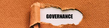 The word Governance revealed under a tear in brown paper.