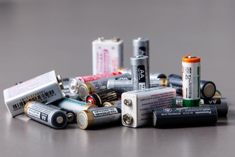 image shows a pile of batteries in all colours and sizes, some standing upright and some laying flat