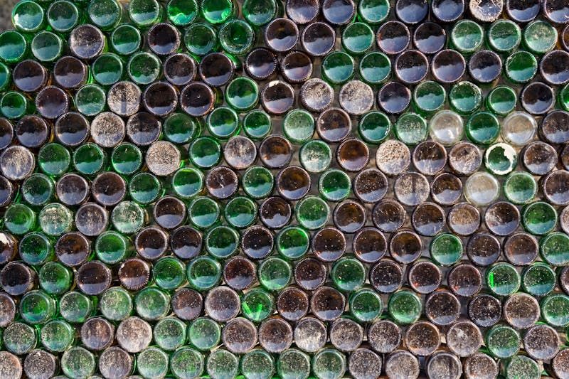 image shows rows of the bottoms of green and brown glass bottles  