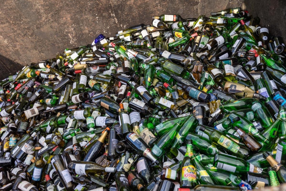 image shows a large pile of glass bottles at a recycling plant