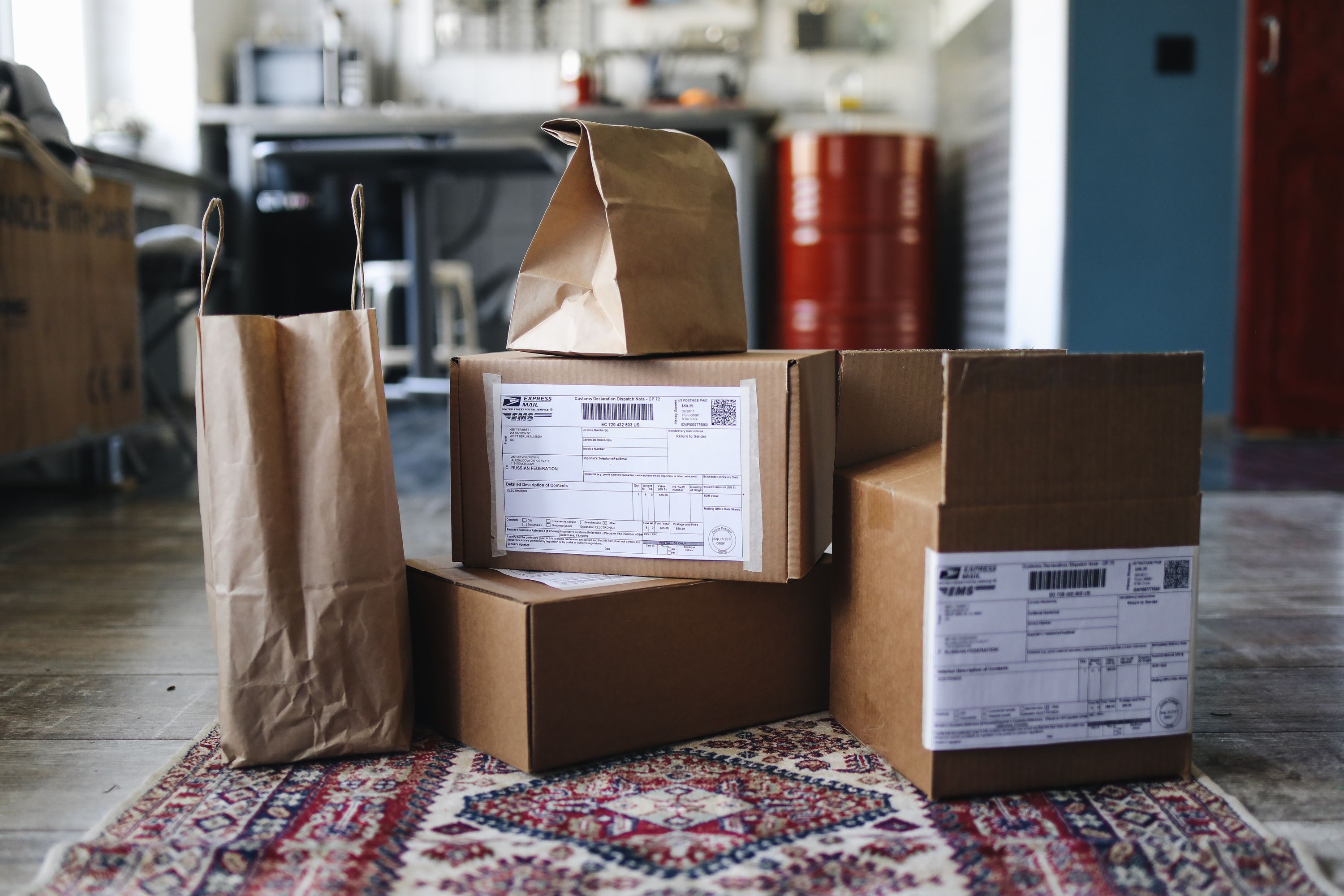 image shows a range of small brown boxes with postal labels and brown bags sitting on a rug