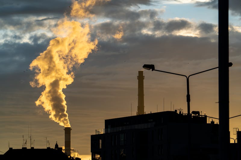 image shows an industrial landscape taken a dusk with smoke billowing out of an industrial chimney