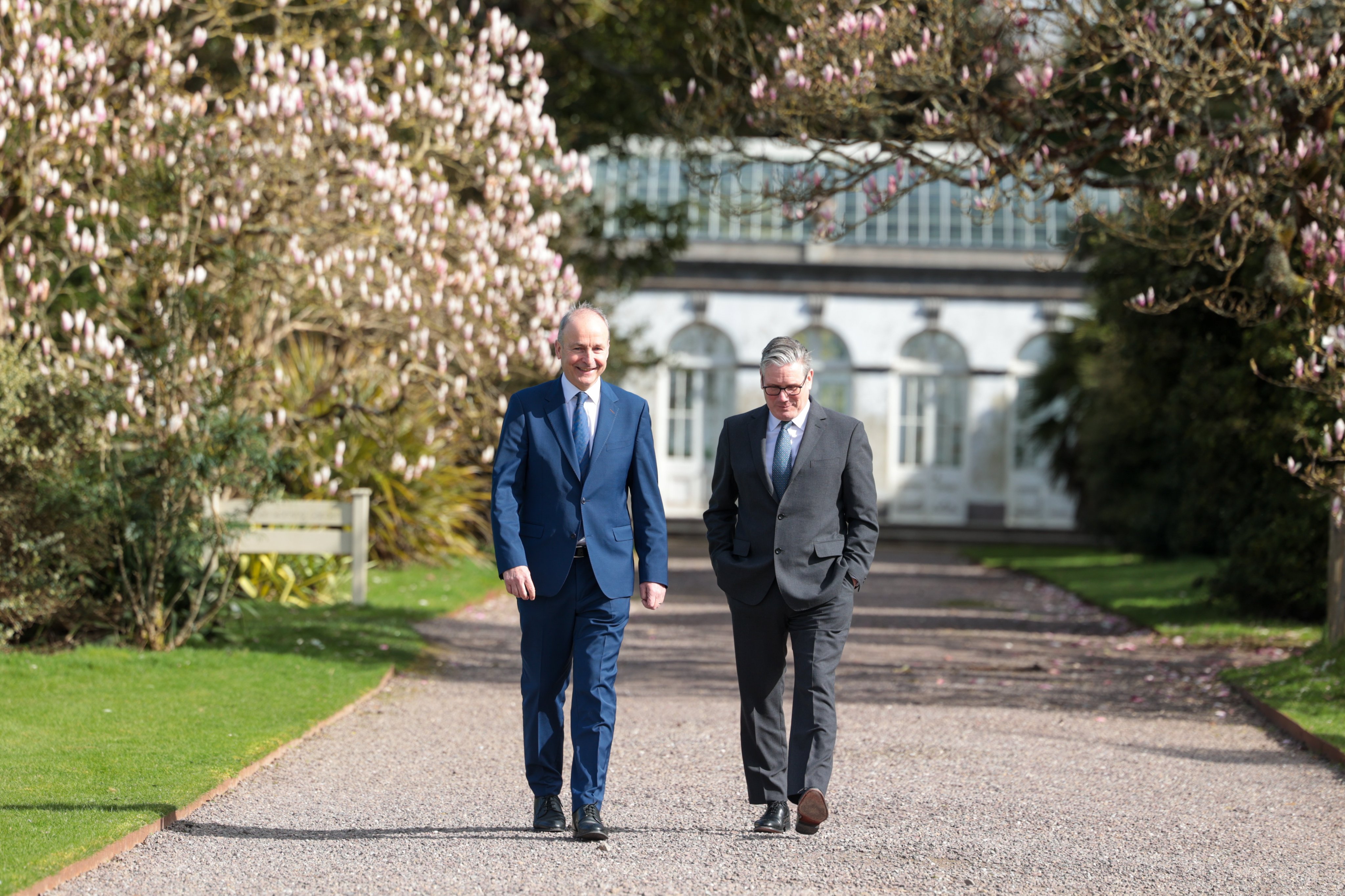 image shows The UK Prime Minister Keir Starmer and the Taoiseach Micheál Martin walking on a park path - they are looking towards the camera