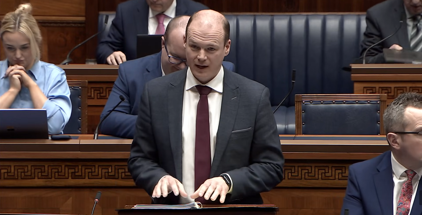 image shows the Communities Minister responding to Members questions in the Assembly chamber 