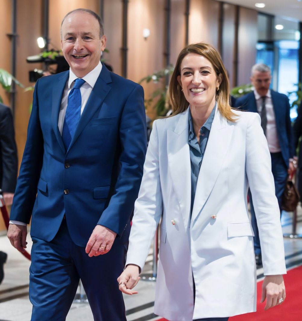 image shows the President of the European Parliament, Roberta Metsola with theTaoiseach Micheál Martin. They are walking together and smiling  