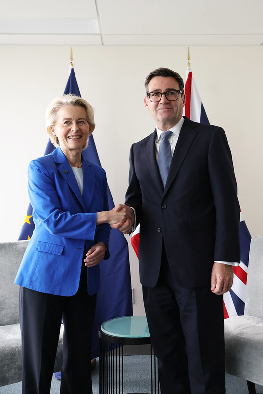 image shows the Prime Minister Andy Burnham (right) pictured with the Ursula von der Leyen, President of the European Commission. The Prime Minister is standing in front of an unfurled Union Jack flag while the President is standing in front of an unfurled EU flag.