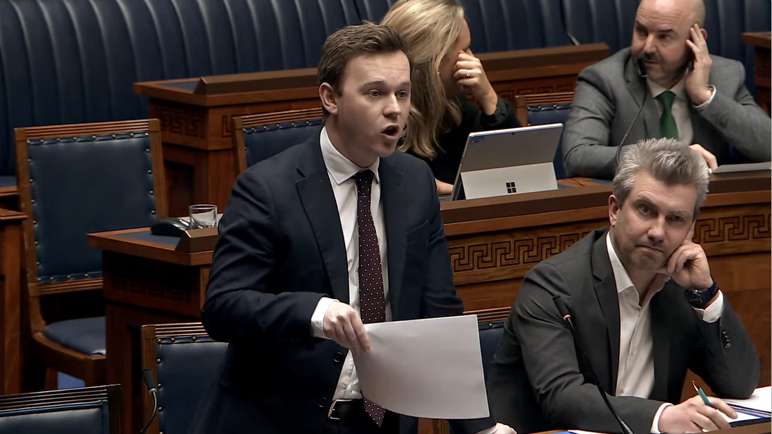 image shows Eoin Tennyson MLA speaking in the Assembly Chamber during a debate on a UK-EU Customs Union.