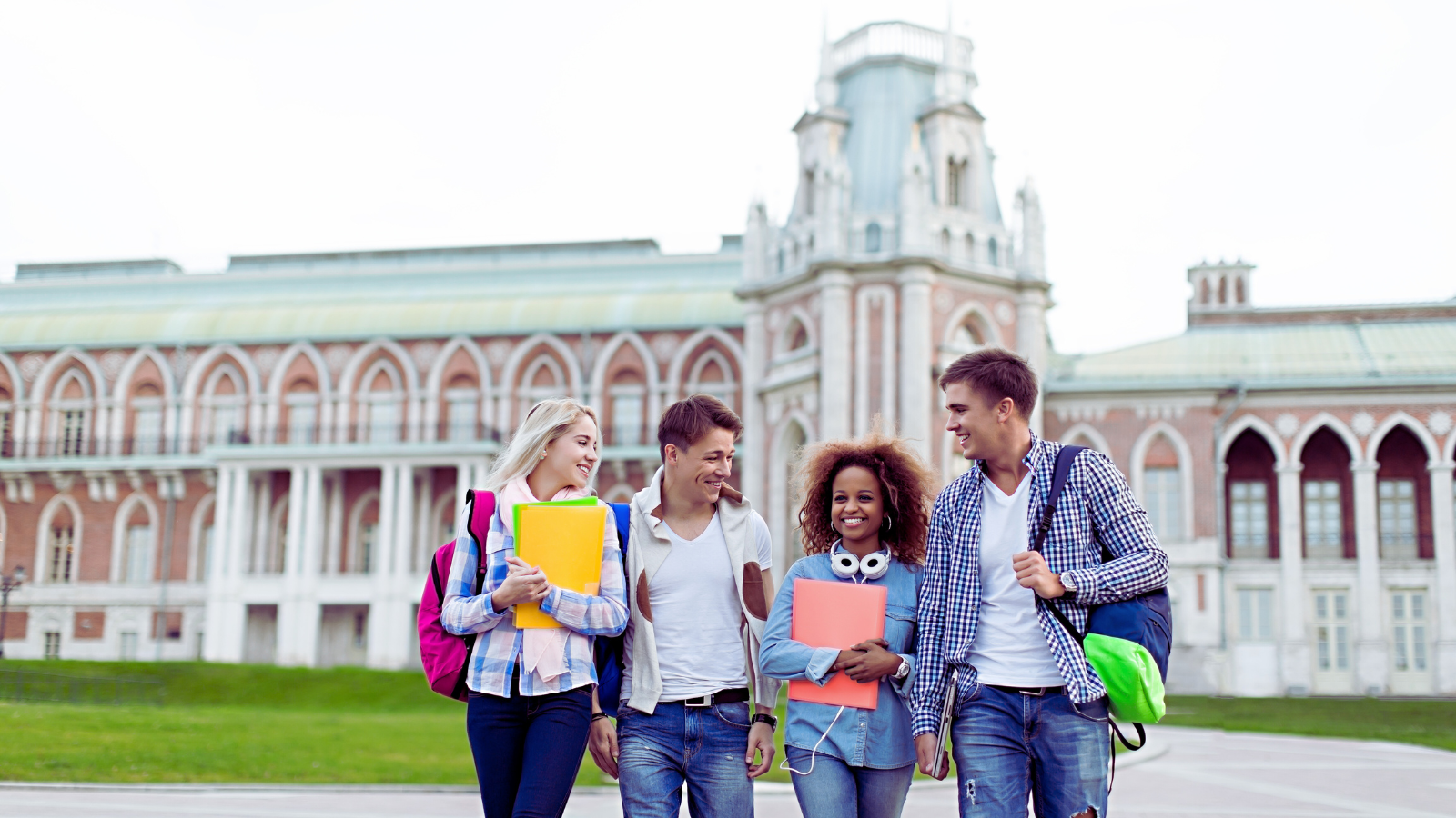 image shows a group of young people standing in front of a college/university