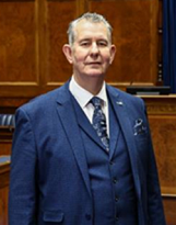 Assembly Speaker, Edwin Poots, standing in front of the Speaker's desk in the Assembly Chamber.