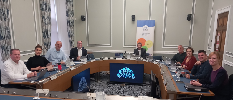 Members of the Education Committee sitting around a table in a committee room of Parliament Buildings