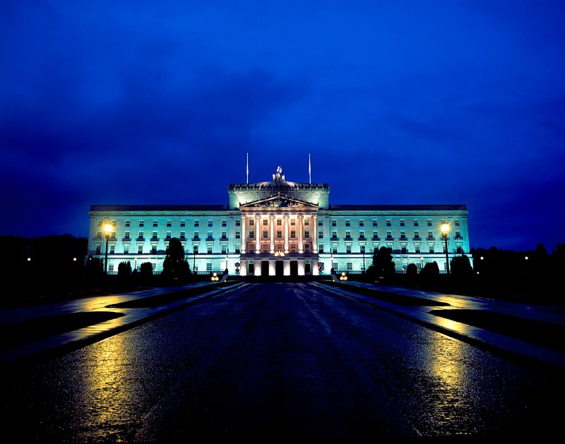 Parliament Buildings during early evening and lit up in green.